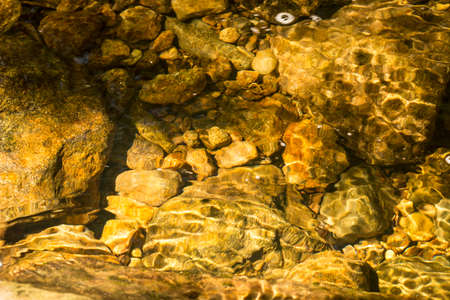 Sunny, sparkling stones in the water on the bottom of Andrews Brook on Mt. Sunapee in Newbury, New...