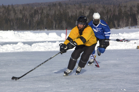 Men's teams compete on the ice at the 11th annual New England Pond Hockey Festival on Haley Pond in Rangeley, Maine.のeditorial素材