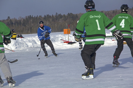 Men's teams compete on the ice at the 11th annual New England Pond Hockey Festival on Haley Pond in Rangeley, Maine.のeditorial素材