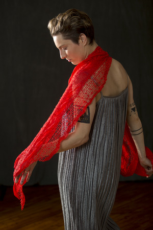 Attractive young woman dancer with short hair, in a silver bag dress, holding a red scarf draped over her shoulders in the studio.の写真素材