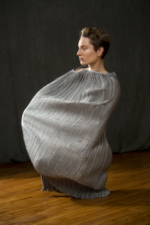 Contemporary young woman dancer with short hair, immersed in a silver bag dress, with only her head emerging from the top, in the studio.の写真素材