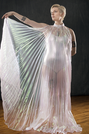 Beautiful young woman dancing in a shimmering transparent cape in the studio.の写真素材