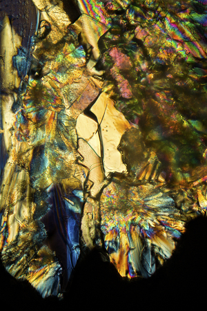 Abstract micrograph of bright gold and blue lysine crystals on a microscope slide at 100x.の写真素材