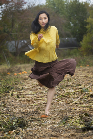 Adult woman dancer in a yellow blouse and brown dress, running in a pumpkin patch on a farm in Ellington, Connecticut.の写真素材