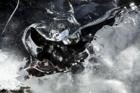 Patterns surrounding a hole in the ice showing dark, open waters of Railroad Brook at Valley Falls Park in Vernon, Connecticut in winter.の写真素材