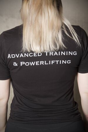 Waist up portrait of young woman from the back, wearing ATP athletic clothing, with the company name on a black shirt.の写真素材