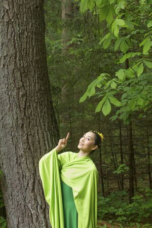 Woman in green dress with long flowing sleeves, dancing in the woods, at the Belding Wildlife Management Area in Vernon, Connecticut.の写真素材