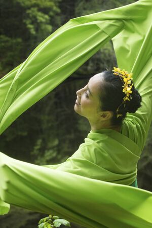 Woman in green dress with long flowing sleeves, dancing on a path in the woods near a pond, at the Belding Wildlife Management Area in Vernon, Connecticut.の写真素材