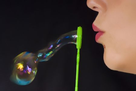 girl blowing and making bubbles in black background