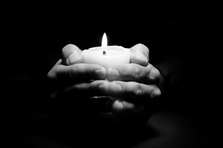 Praying Hands with candle in dark background black and whiteの写真素材