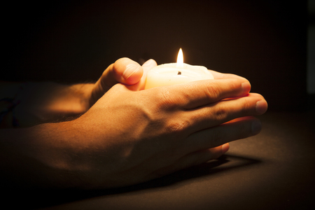 Praying Hands with candle in black backgroundの写真素材