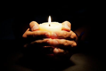 Praying Hands with candle in dark backgroundの写真素材