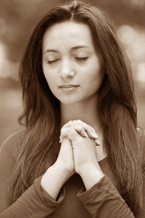 Woman hands praying with a blible in his legs Outdoors, sepia black and whiteの写真素材