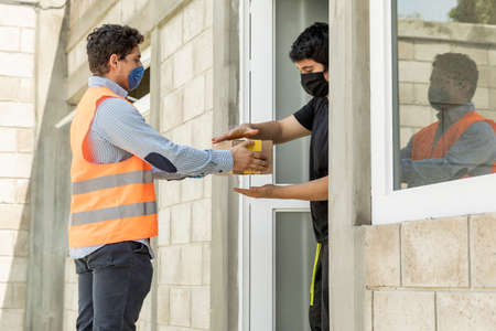 Handsome and elegant man delivering a package. Using mouth cover during the COVID-19 pandemic