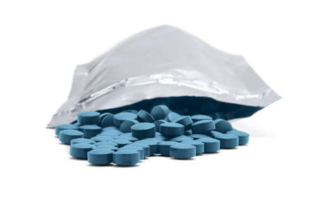 Medicine tablets, vitamins of blue color coming out of a resealable aluminum bag on white background