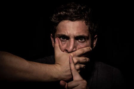 Scared man about to be killed on dark background. dramatic lightsの写真素材