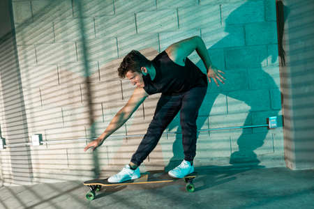 Young and attractive man skating in a big cellar. dramatic lights