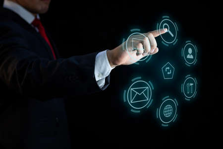 Businessman hand in elegant suit selecting virtual reality and internet applications on dark...
