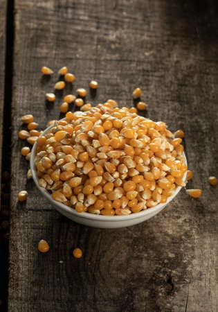 Detail of a lot of raw corn in white plate on a wooden table