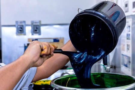 Detail of hands of printing industry worker while mixing an ink color.