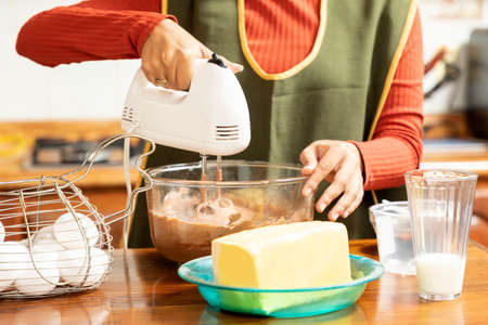 Young Latina woman making homemade cakes in her home kitchen during a COVID-19 pandemic.の写真素材