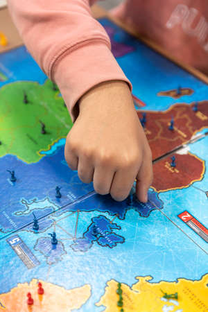 Group of youths with face masks during COVID-19 disease quarantine playing a board game.の写真素材