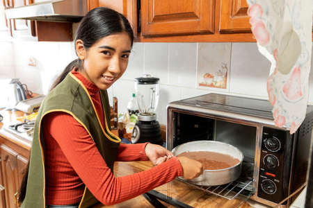 Young Latina woman making homemade cakes in her home kitchen during a COVID-19 pandemic.の写真素材