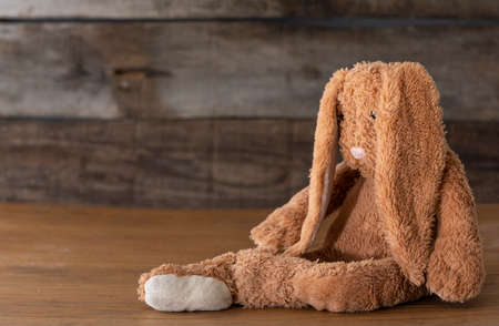 toys of a child in the house. depressed teddy bunny over the wooden table