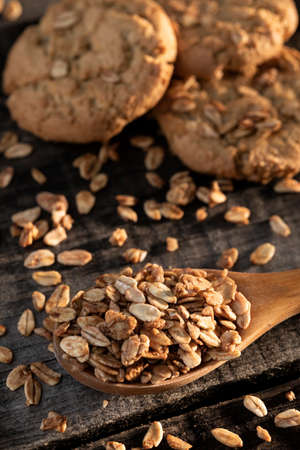 Homemade cookies with whole grain oatmeal and spoon on rustic wooden table.