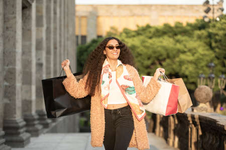 Beautiful young woman wearing fashionable clothes walking on the street
