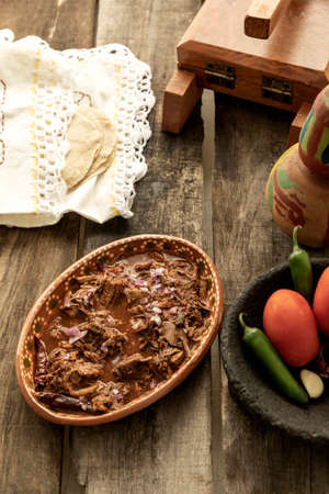 Plate of birria with tortillas on a rustic table. Traditional Mexican food