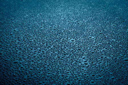 Water drops texture on dark surface with blue lights.の写真素材