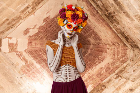 Young Mexican woman with typical costume and catrina makeup for Dia de Muertos party. Abstract...