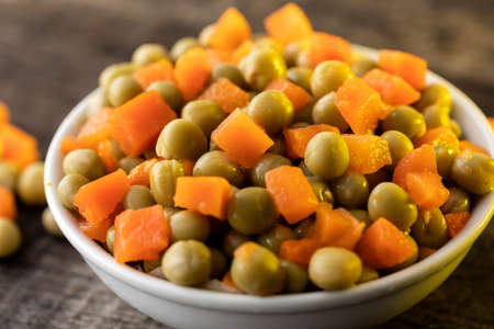 White plate on rustic table with corn, peas and carrots.の写真素材