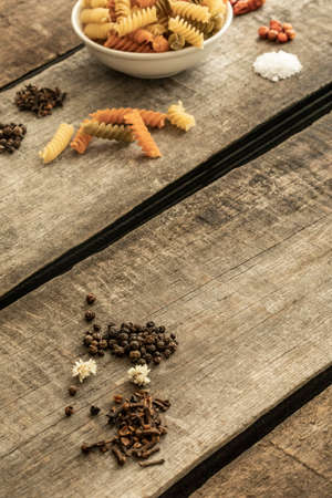 Detail of pasta on a deep dish and other ingredients for sauce on a wooden table