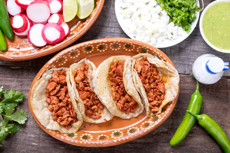 Tacos of meat to the shepherd or marinated. Typical mexican food in a rustic table full of sauces...