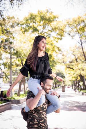 Young couple man and woman in love, having fun and kissing in the public park.