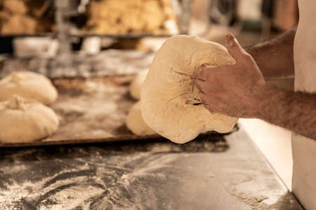 hands of the teacher baker in the bread production on the table