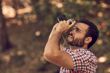 Portrait of handsome bearded photographer and camera taking photos outdoor.