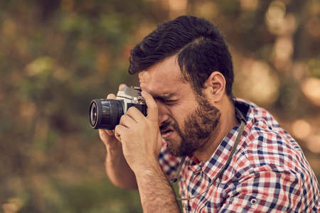 Portrait of handsome bearded photographer and camera taking photos outdoor.の写真素材