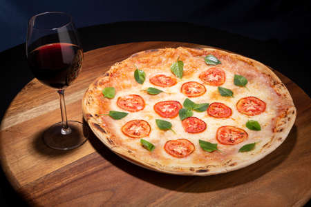 detail of wood table with a delicious pizza and a glass of wine. gourmet food
