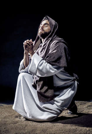 Jesus Christ praying to God consecration the bread and grapes in the dark black night. Black and...