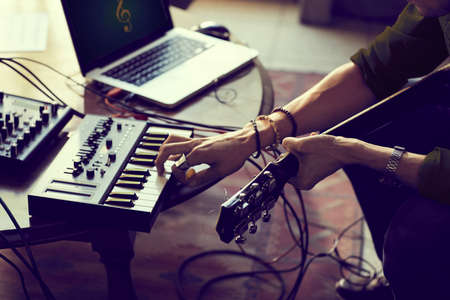 Casual detail inside of man playing guitar in an audio studio