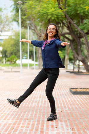 Beautiful young latin woman with glasses, playing and dancing for happiness in outdoor park
