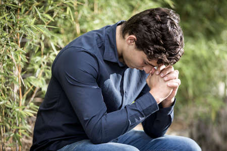 Young businessman reading the Sacred Bible in outdoor garden