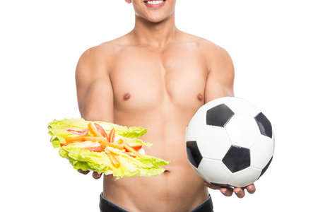 Young and healthy man with soccer ball and an apple in his hands in white backgroundの写真素材