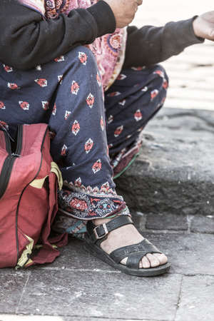 Detail of the feet of the homeless woman asking a coin to a homeless person