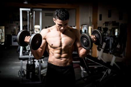 Young man exercising in dark and old gymの写真素材