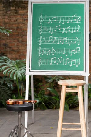 Teacher teaching musical notes on green chalkboard
