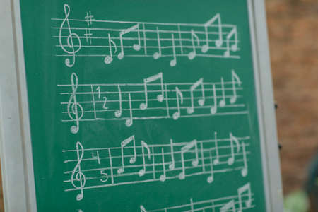 Teacher teaching musical notes on green chalkboardの写真素材